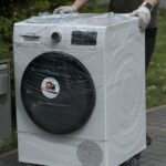 Pralka automatyczna w czasie transportu z mieszkania do samochodu na wózku z kółkami