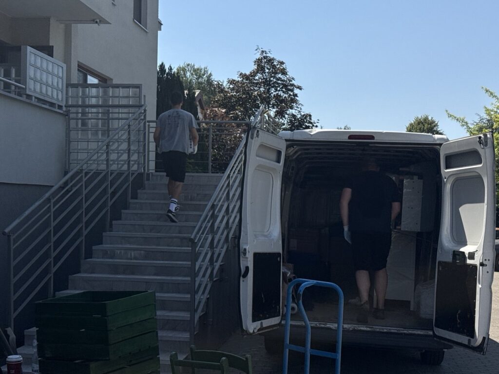 Pracownicy Go Przeprowadzki wnoszą kartony i meble schodami do budynku podczas przeprowadzki w Warszawie